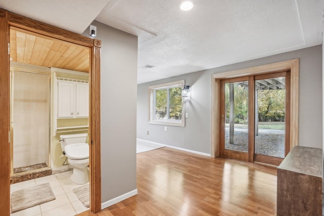 interior space with toilet, wood-type flooring, and a textured ceiling