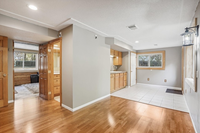 unfurnished living room with a textured ceiling and light hardwood / wood-style flooring