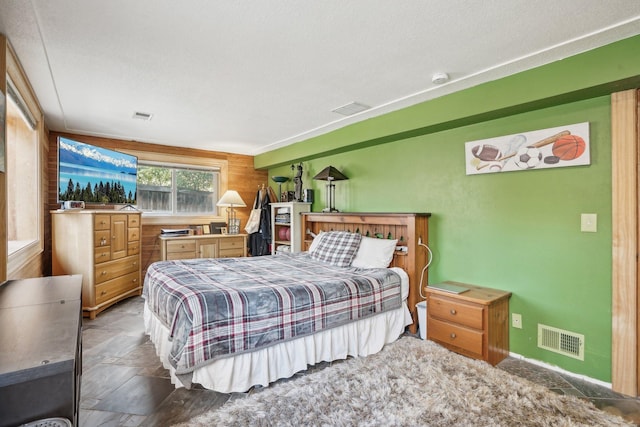 bedroom featuring a textured ceiling and wood walls