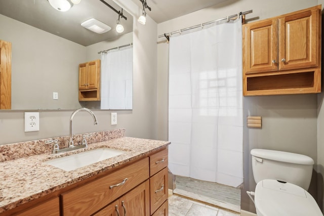 bathroom featuring vanity, rail lighting, toilet, and walk in shower