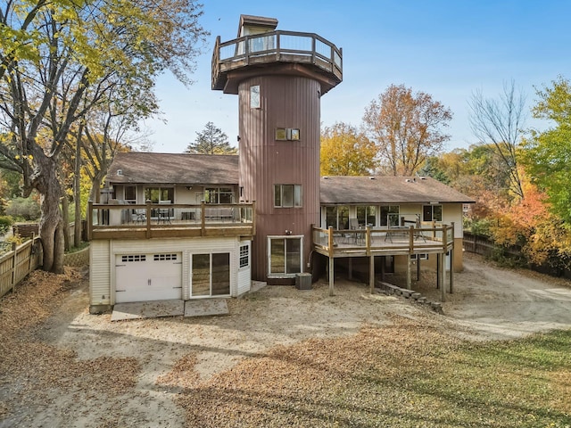 back of property with a balcony, a deck, and a garage