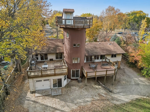 back of property with a garage, a balcony, and a wooden deck