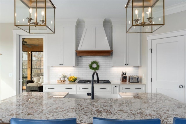 kitchen featuring white cabinetry, custom range hood, and pendant lighting