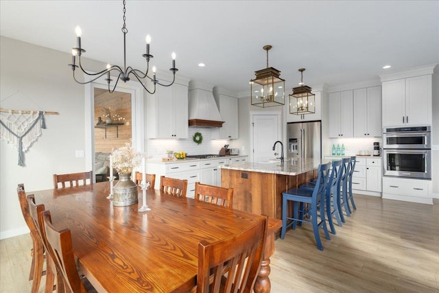 dining space with ornamental molding, sink, light hardwood / wood-style flooring, and a notable chandelier