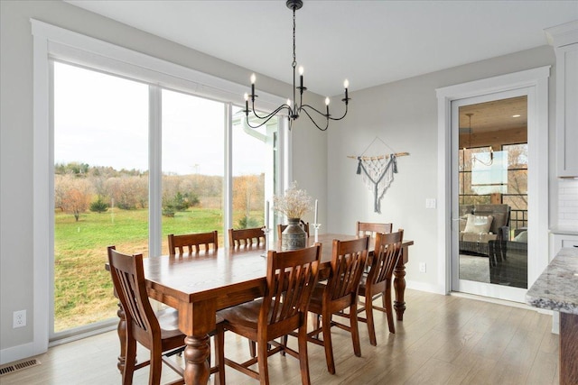 dining space with a wealth of natural light, a chandelier, and light wood-type flooring