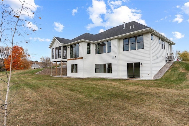 rear view of house featuring central air condition unit and a lawn