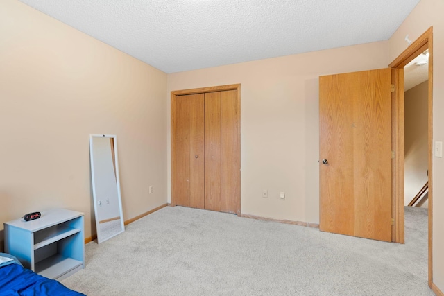 unfurnished bedroom featuring a closet, carpet floors, a textured ceiling, and baseboards