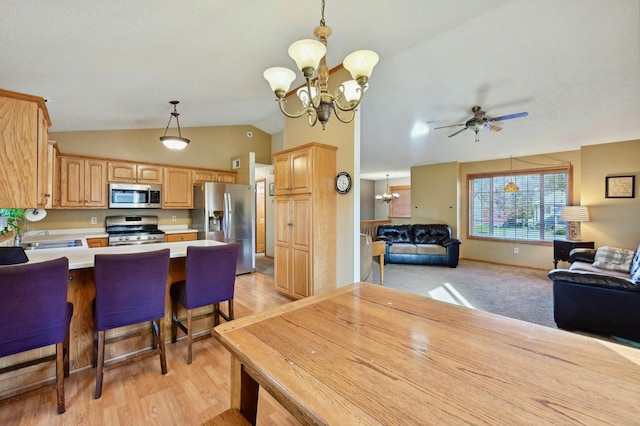 dining room with sink, vaulted ceiling, light wood-type flooring, and ceiling fan with notable chandelier