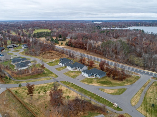 aerial view of property's location with a forest, nearby suburban area, and a nearby body of water