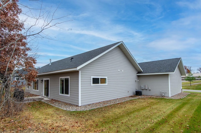 rear view of house featuring central air condition unit and a yard