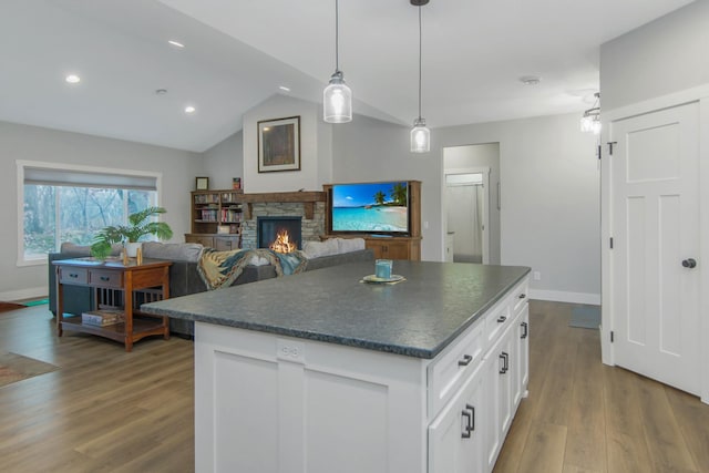 kitchen with pendant lighting, a center island, vaulted ceiling, white cabinetry, and light wood-type flooring