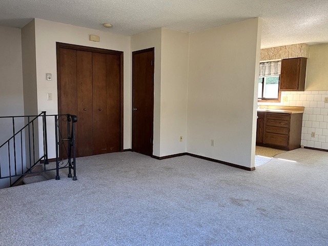 interior space with a textured ceiling, two closets, and light colored carpet