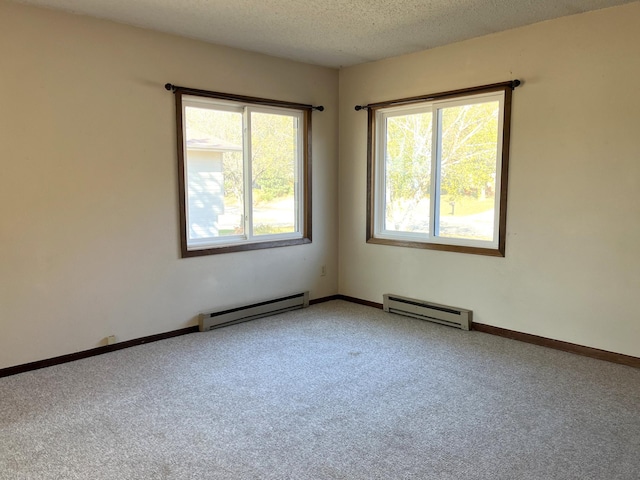 carpeted spare room with a textured ceiling and a baseboard heating unit