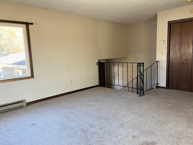 carpeted empty room featuring a textured ceiling and baseboard heating