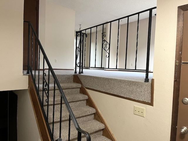 stairs featuring a textured ceiling and carpet floors