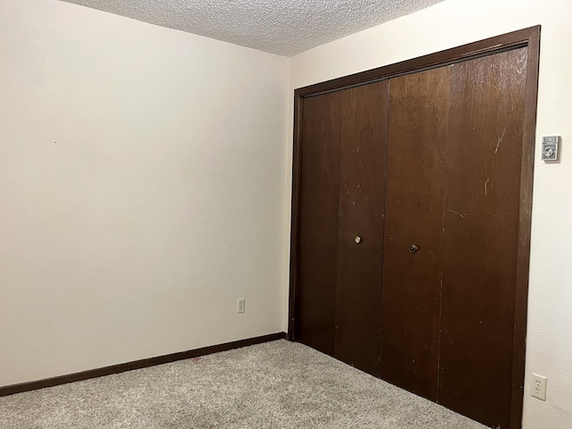 unfurnished bedroom with a closet, a textured ceiling, and carpet flooring