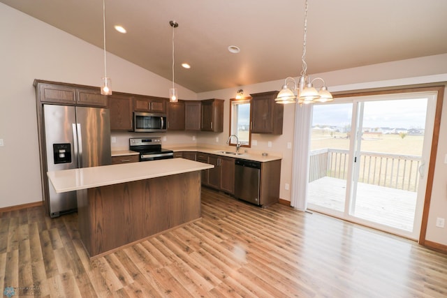 kitchen with appliances with stainless steel finishes, sink, a center island, vaulted ceiling, and pendant lighting