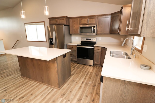 kitchen with vaulted ceiling, light hardwood / wood-style flooring, stainless steel appliances, sink, and decorative light fixtures