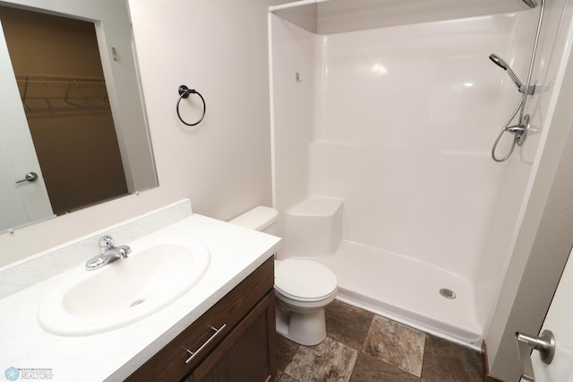 bathroom featuring vanity, a shower, and toilet