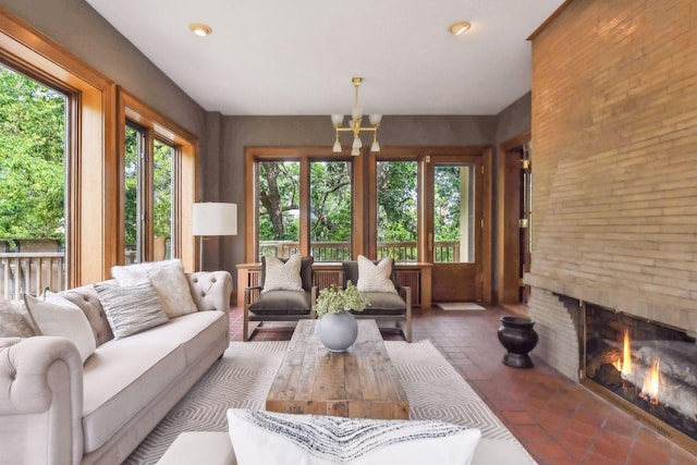 living room featuring a notable chandelier and a brick fireplace