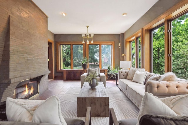 sunroom / solarium featuring a wealth of natural light, a notable chandelier, and a brick fireplace