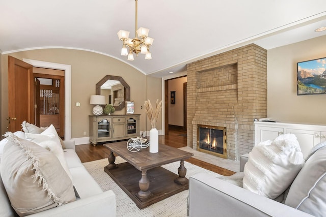 living room with a chandelier, a brick fireplace, and wood-type flooring