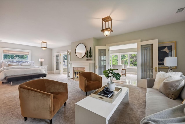 carpeted bedroom with french doors and a tiled fireplace