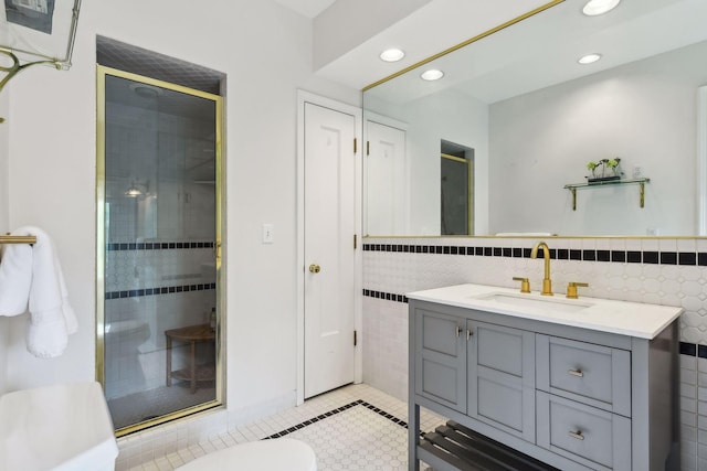 bathroom featuring a shower with door, vanity, tile patterned flooring, and tile walls