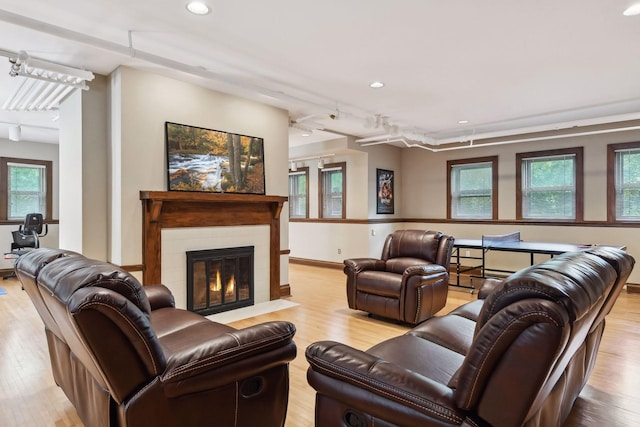 living room featuring a tile fireplace, track lighting, light wood-type flooring, and plenty of natural light