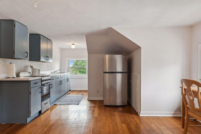 kitchen with gray cabinets, a textured ceiling, light hardwood / wood-style flooring, and stainless steel appliances