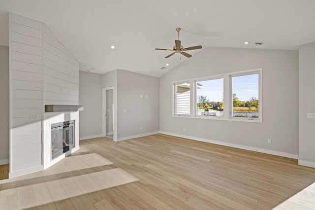 unfurnished living room with vaulted ceiling, a fireplace, light wood-type flooring, and ceiling fan