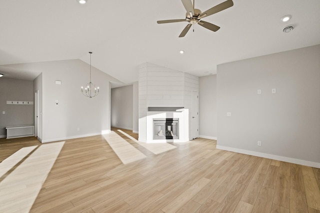 unfurnished living room with light hardwood / wood-style floors, lofted ceiling, a large fireplace, and ceiling fan with notable chandelier