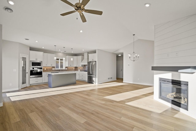 interior space with white cabinets, hanging light fixtures, light hardwood / wood-style flooring, stainless steel appliances, and a center island