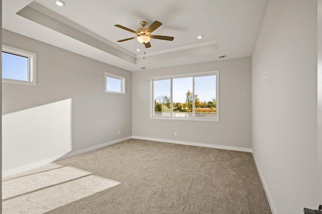 unfurnished room with ornamental molding, ceiling fan, carpet flooring, and a raised ceiling