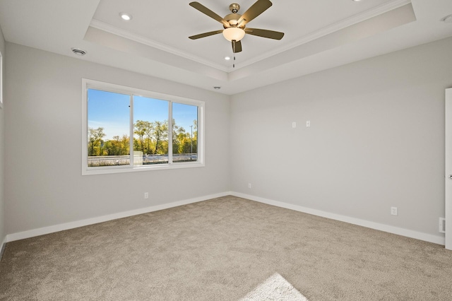 unfurnished room with ornamental molding, ceiling fan, carpet floors, and a raised ceiling