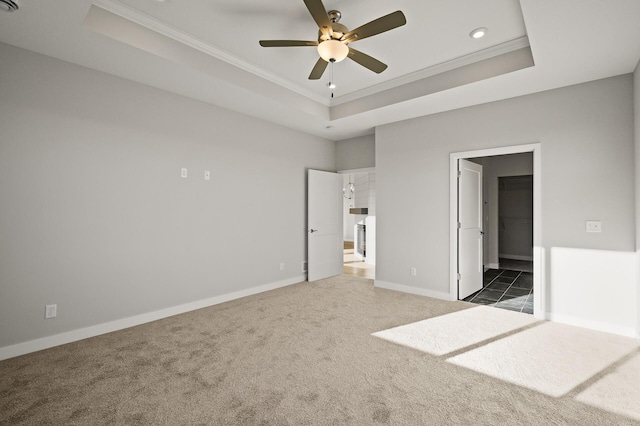 unfurnished bedroom featuring crown molding, dark colored carpet, a tray ceiling, and ceiling fan