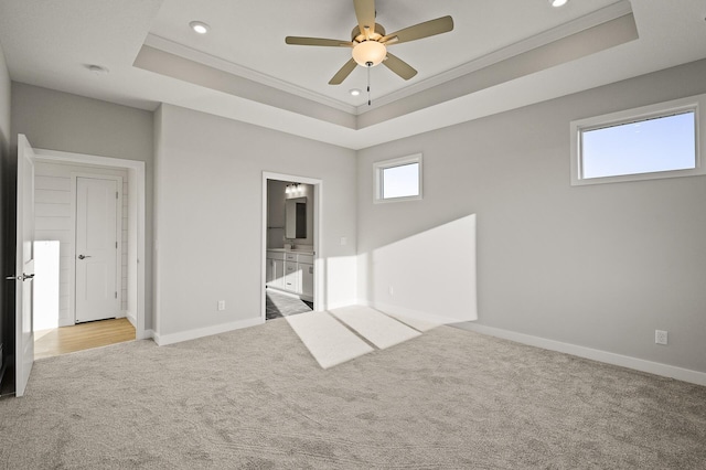 unfurnished bedroom featuring connected bathroom, ceiling fan, ornamental molding, and a raised ceiling