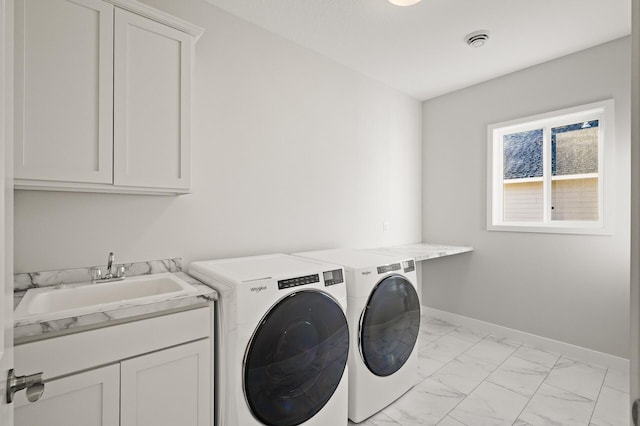 clothes washing area featuring sink, washer and dryer, and cabinets