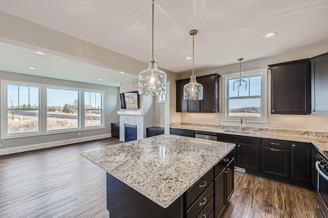 kitchen with dishwasher, wood-type flooring, sink, a center island, and a fireplace