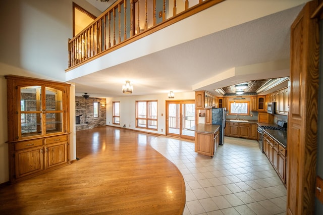 kitchen with appliances with stainless steel finishes, ceiling fan, sink, light hardwood / wood-style floors, and a kitchen island