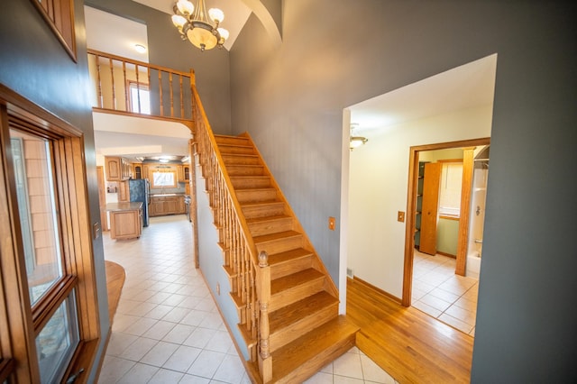 stairway with tile patterned flooring, a high ceiling, and an inviting chandelier