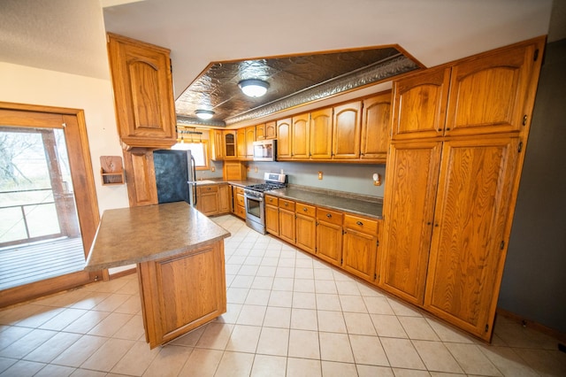 kitchen with a kitchen island, fridge, a healthy amount of sunlight, and stainless steel range with gas stovetop