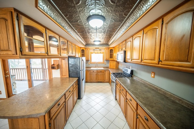 kitchen featuring a center island, sink, light tile patterned floors, appliances with stainless steel finishes, and a tray ceiling