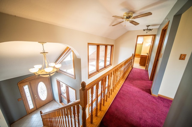 corridor with light colored carpet, a wealth of natural light, lofted ceiling, and a notable chandelier