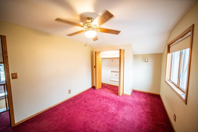 unfurnished bedroom featuring dark carpet, a closet, lofted ceiling, and ceiling fan