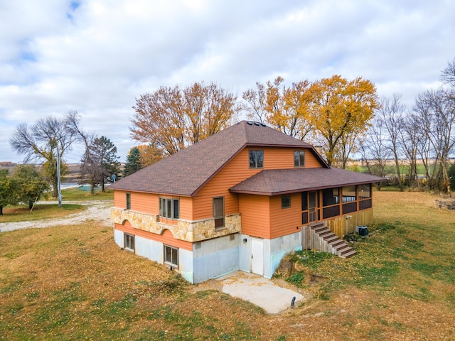 view of side of home featuring a sunroom, cooling unit, and a yard