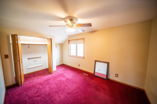 unfurnished bedroom featuring a textured ceiling, dark carpet, ceiling fan, and lofted ceiling