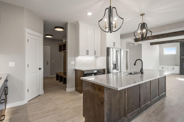 kitchen with an island with sink, stainless steel refrigerator with ice dispenser, light hardwood / wood-style flooring, sink, and white cabinets