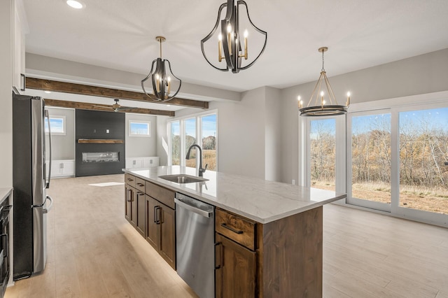 kitchen featuring a center island with sink, beamed ceiling, sink, and appliances with stainless steel finishes