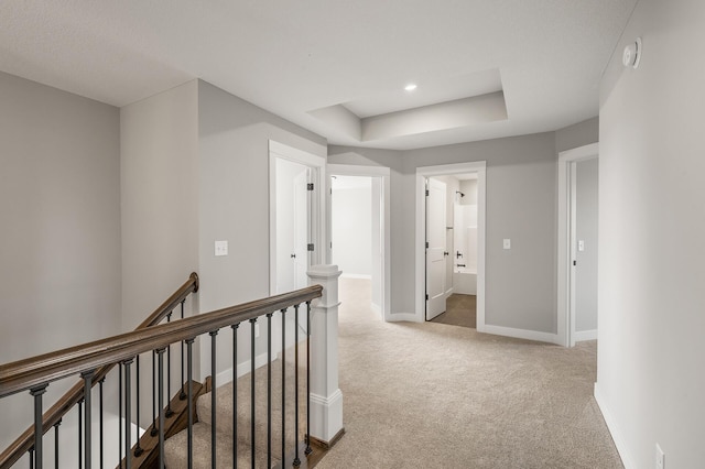 hall with carpet floors and a raised ceiling